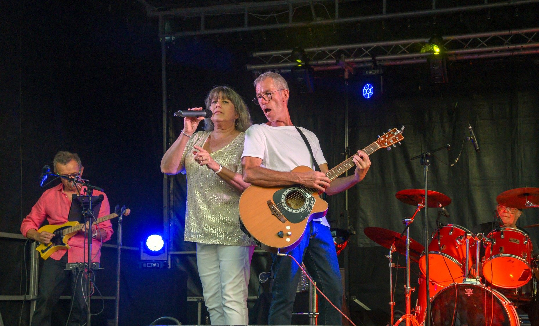 La chanteuse et le guitariste d'Arkanciel chantant ensemble au micro sur scène.
